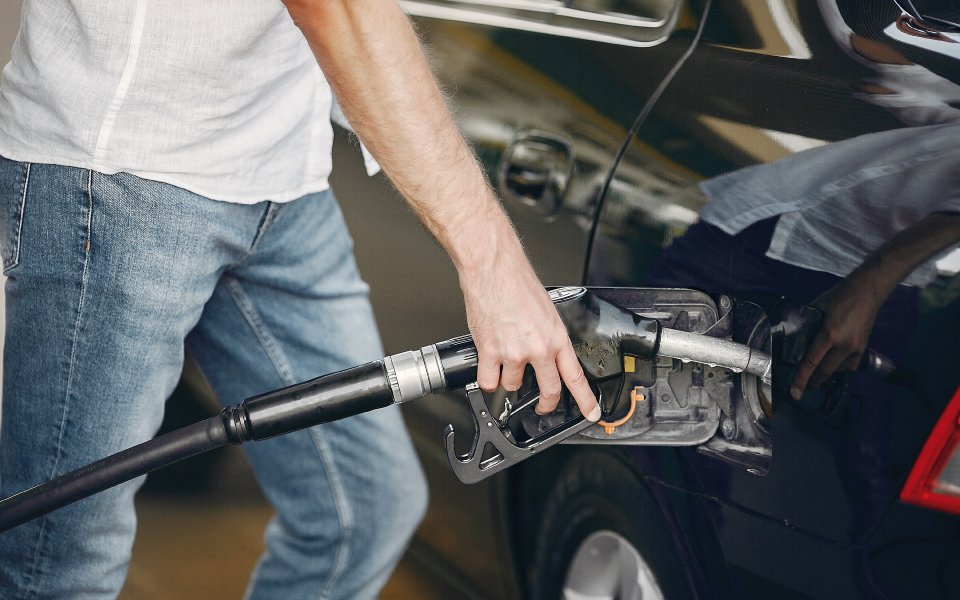 Persona introduciendo la manguera de combustible en el depósito de un coche.